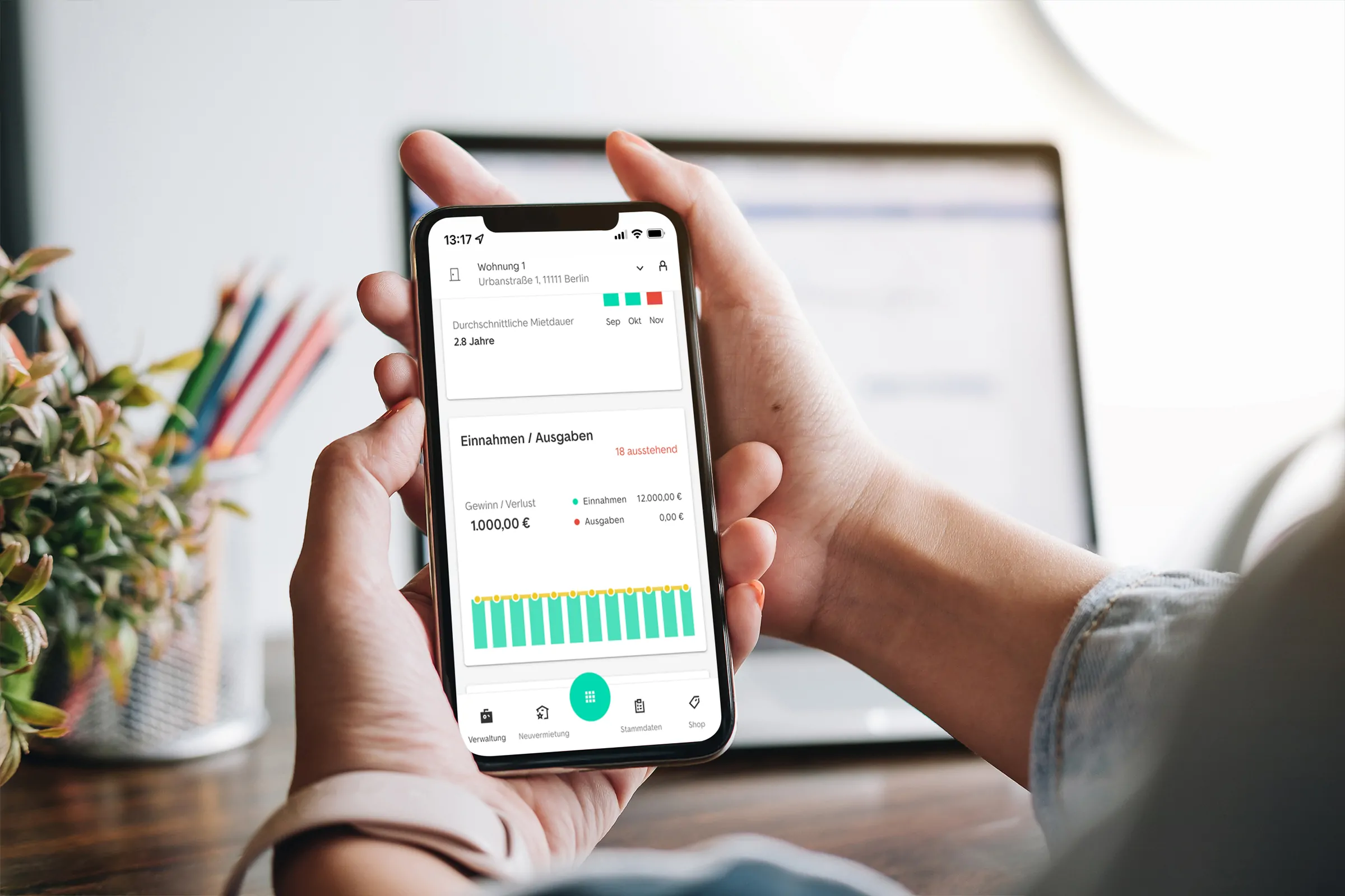 Eine Person hält ein Smartphone in der Hand welches einen Screenshot der Vermietet.de Software enthält, worauf die Einnahmen und Ausgaben mittels eines Grafen skizziert sind.